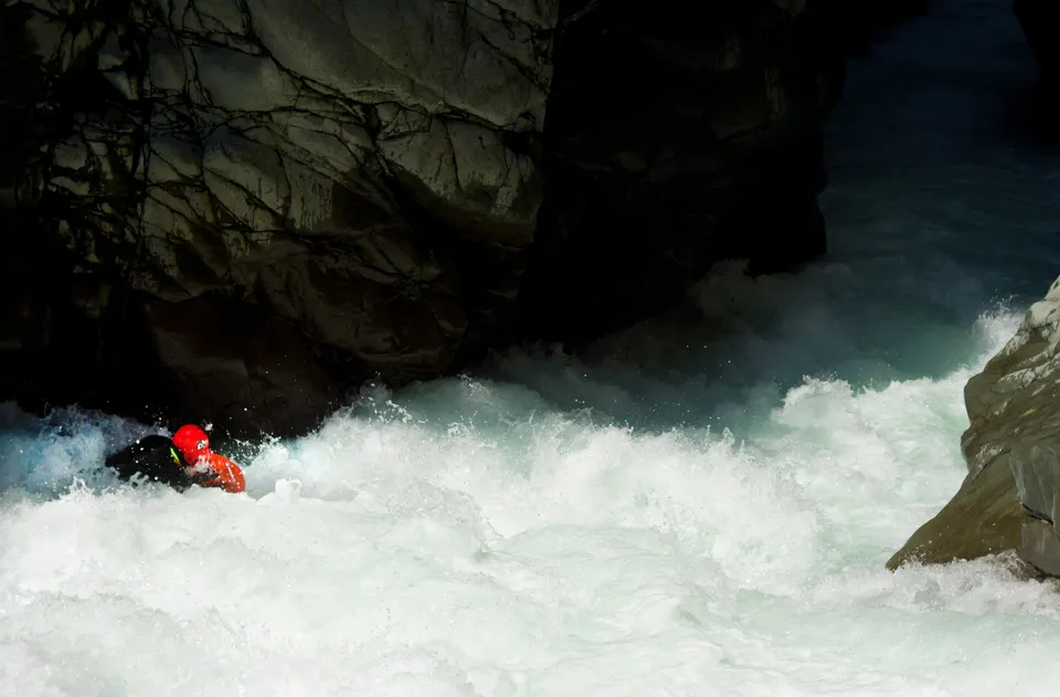 Josh Galt riverboarding a white chute under a black rock wall in a Japanese gorge