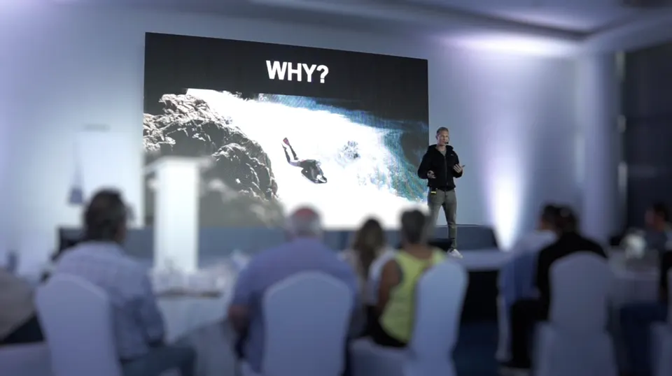 Josh Galt on stage beside a slide of his riverboarding, the word WHY above it